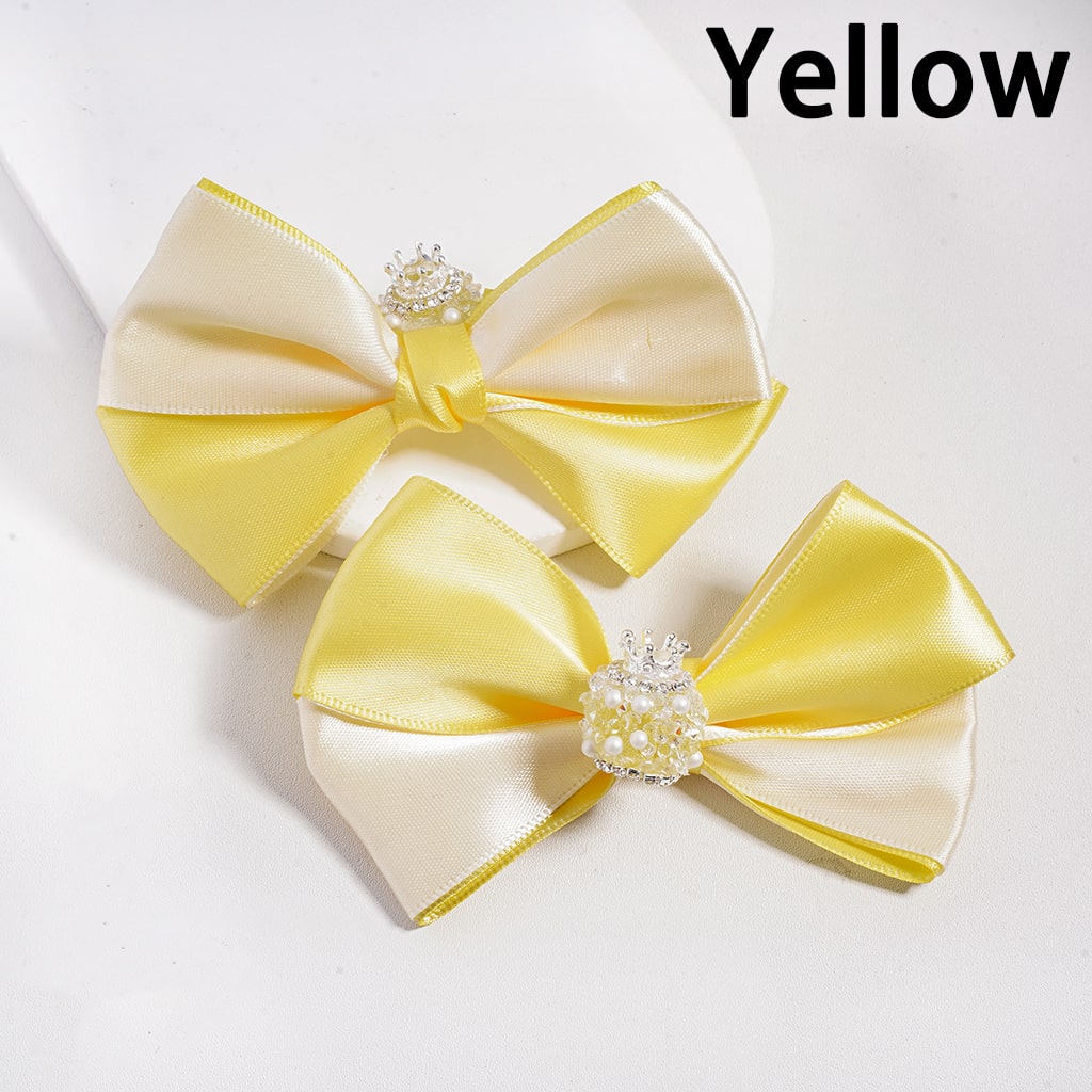 Two yellow and white satin bows with decorative centers on a white background.

