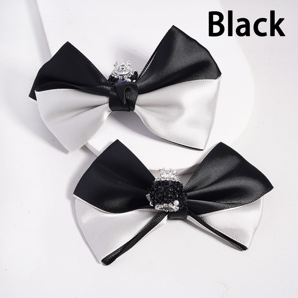 Two black and white bow ties with a central gemstone on a light gray background.

