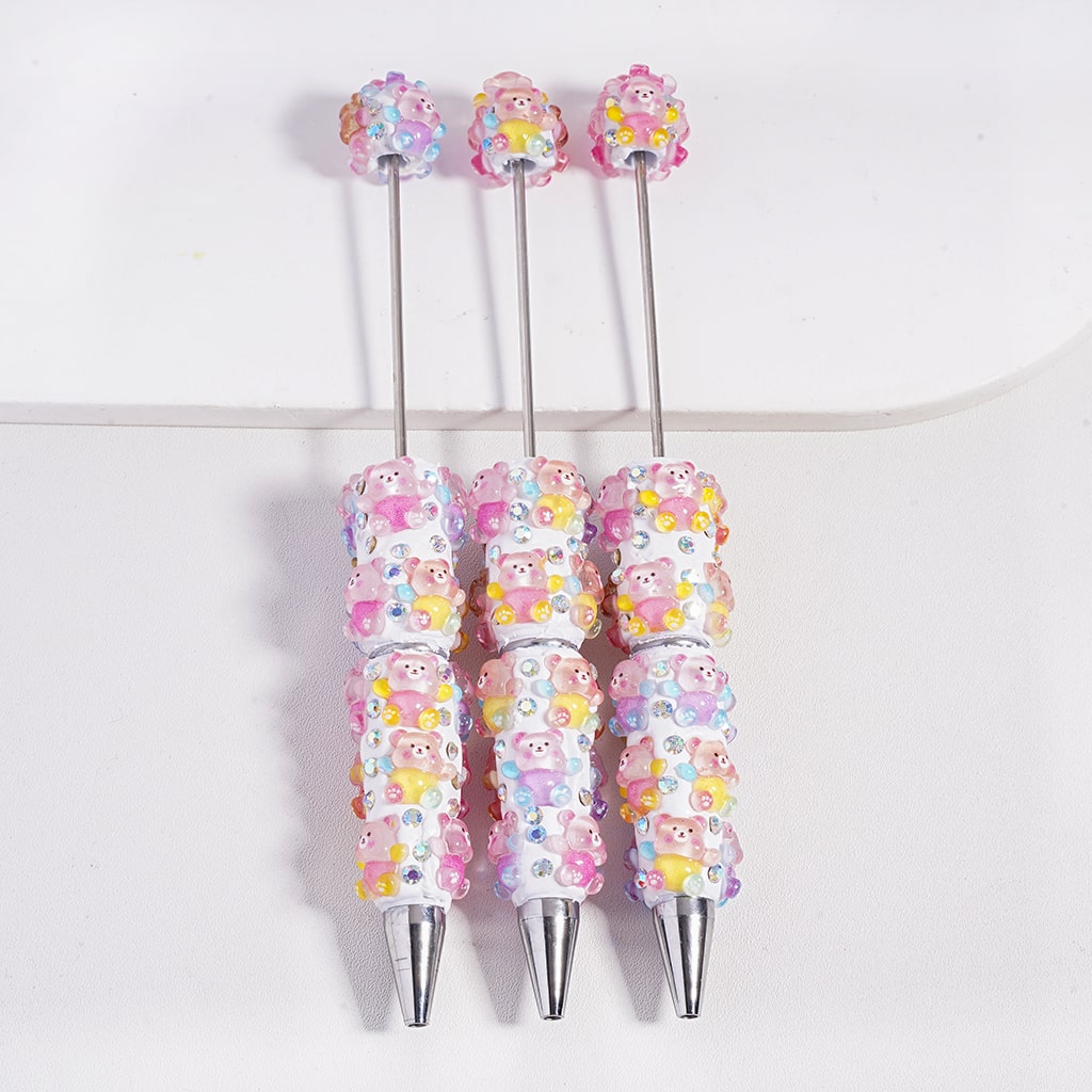 Set of three decorative pens with colorful bead designs on a white background