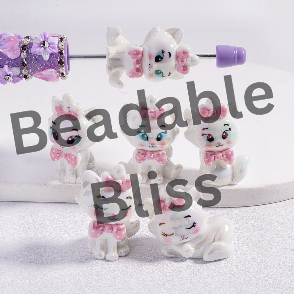 Set of small cat figurines with pink bows on a white background, branded 'beadablebliss'.