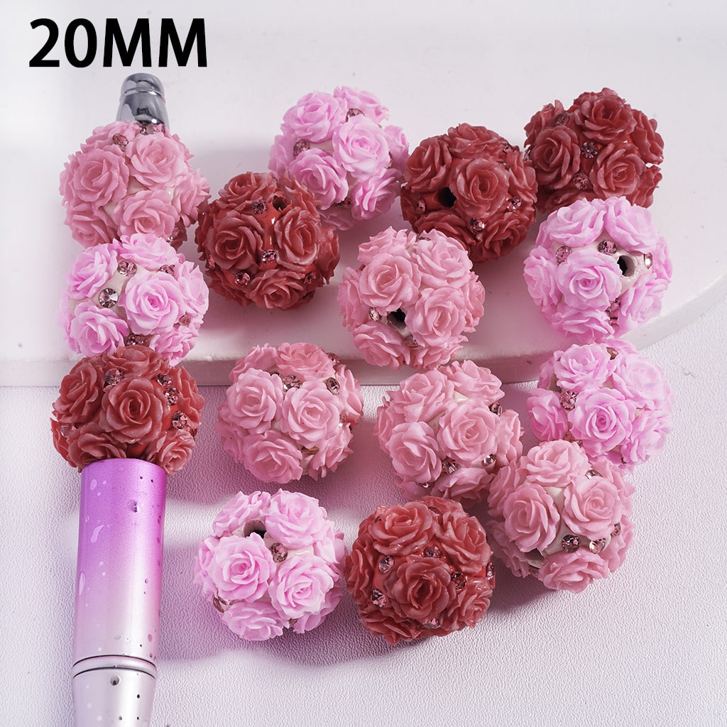 Pink and red rose-shaped beads with a pen for scale on a white background