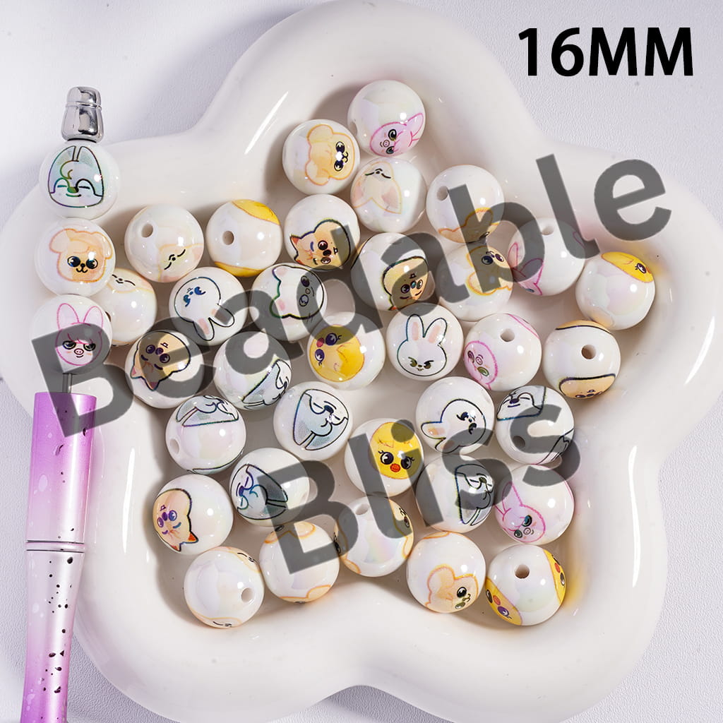 White beads with cartoon faces on a white dish with a pink pen.