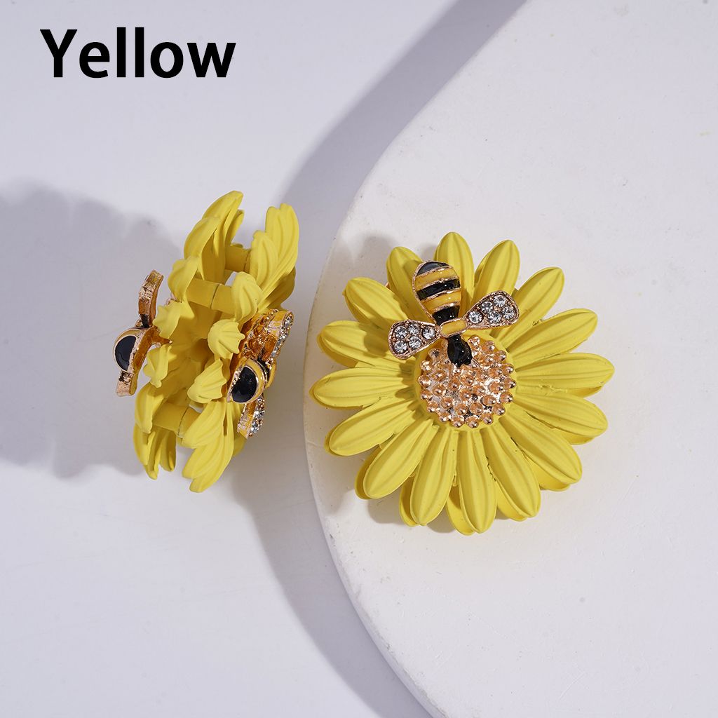 Yellow flower-shaped earrings with bee design on a white background