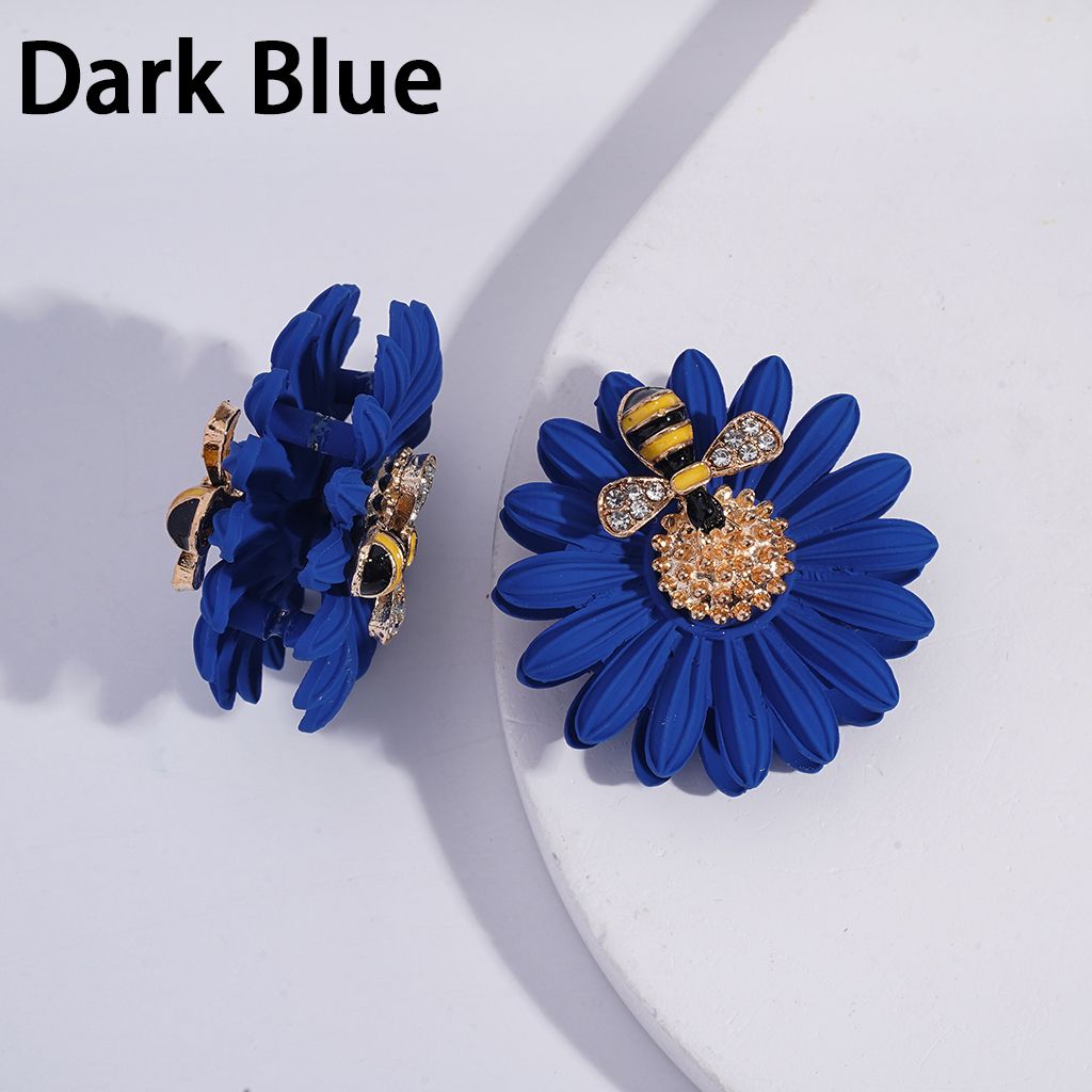 Dark blue flower-shaped earrings with bee design on a white background