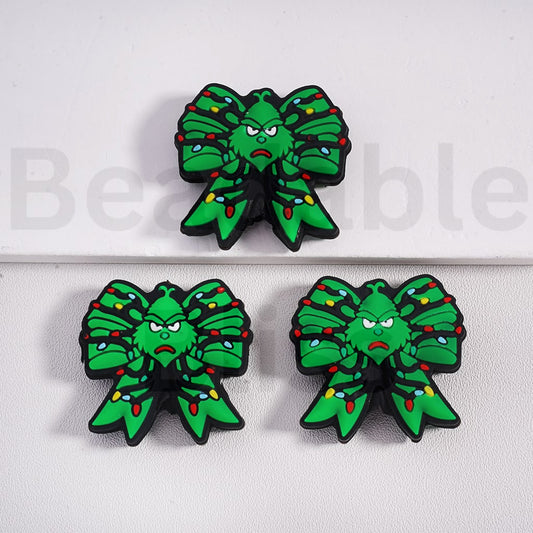 Green bow-shaped earrings with a face design on a white background

