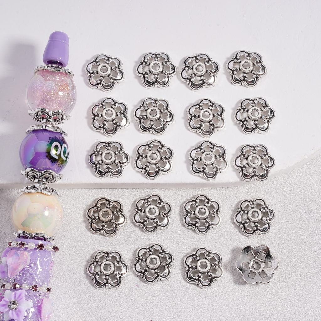 Set of silver floral beads with a decorative purple and white beaded item on a light gray background

