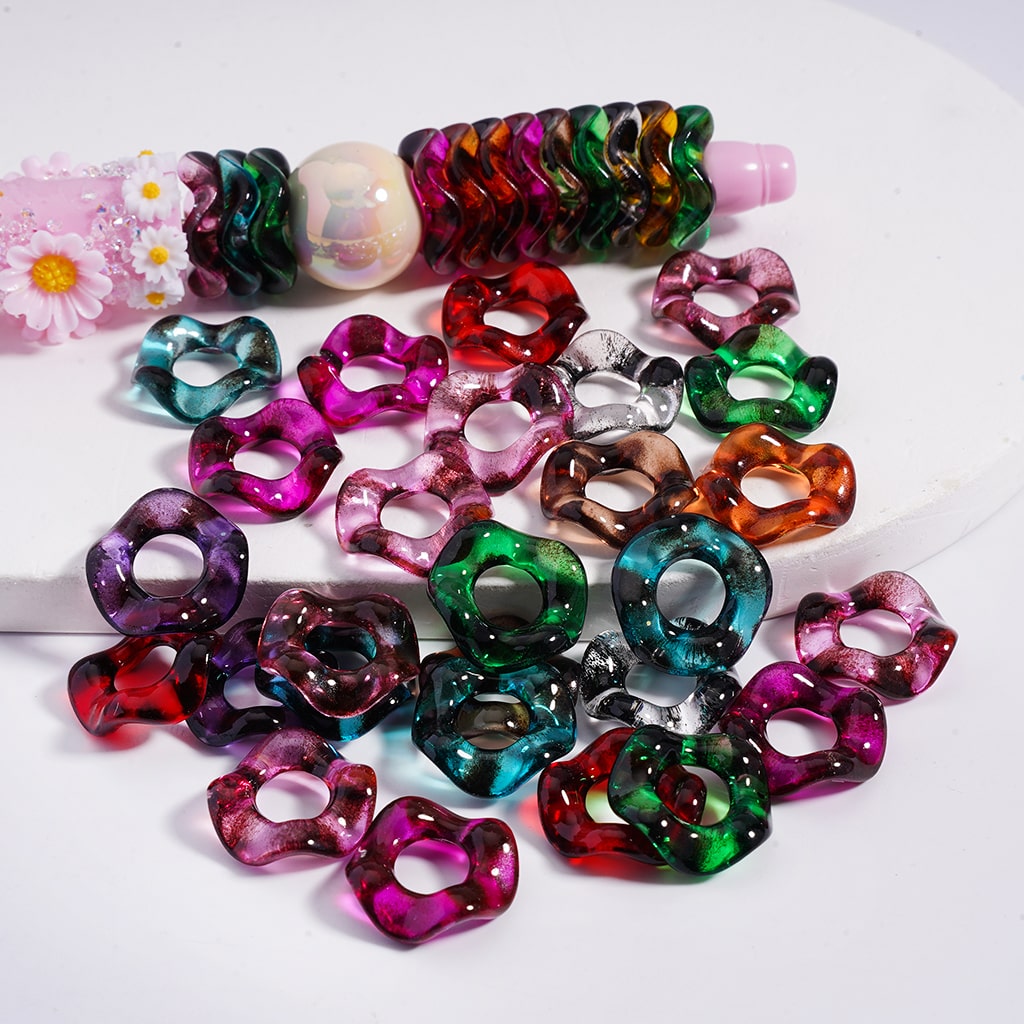 Colorful plastic rings on a white surface with a small flower in the background

