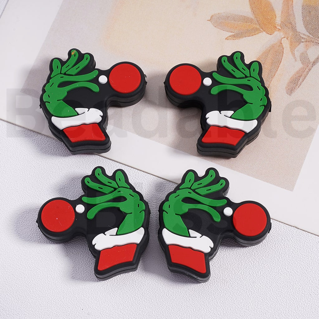 Four Christmas-themed keychains with green wreaths, red circles, and white details on a light background.


