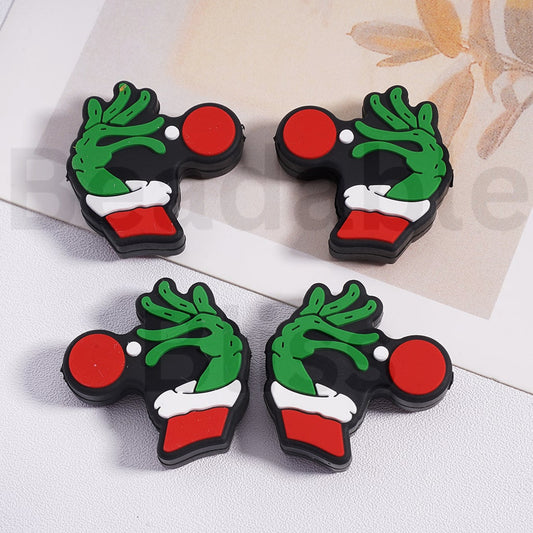 Four Christmas-themed keychains with green wreaths, red circles, and white details on a light background.

