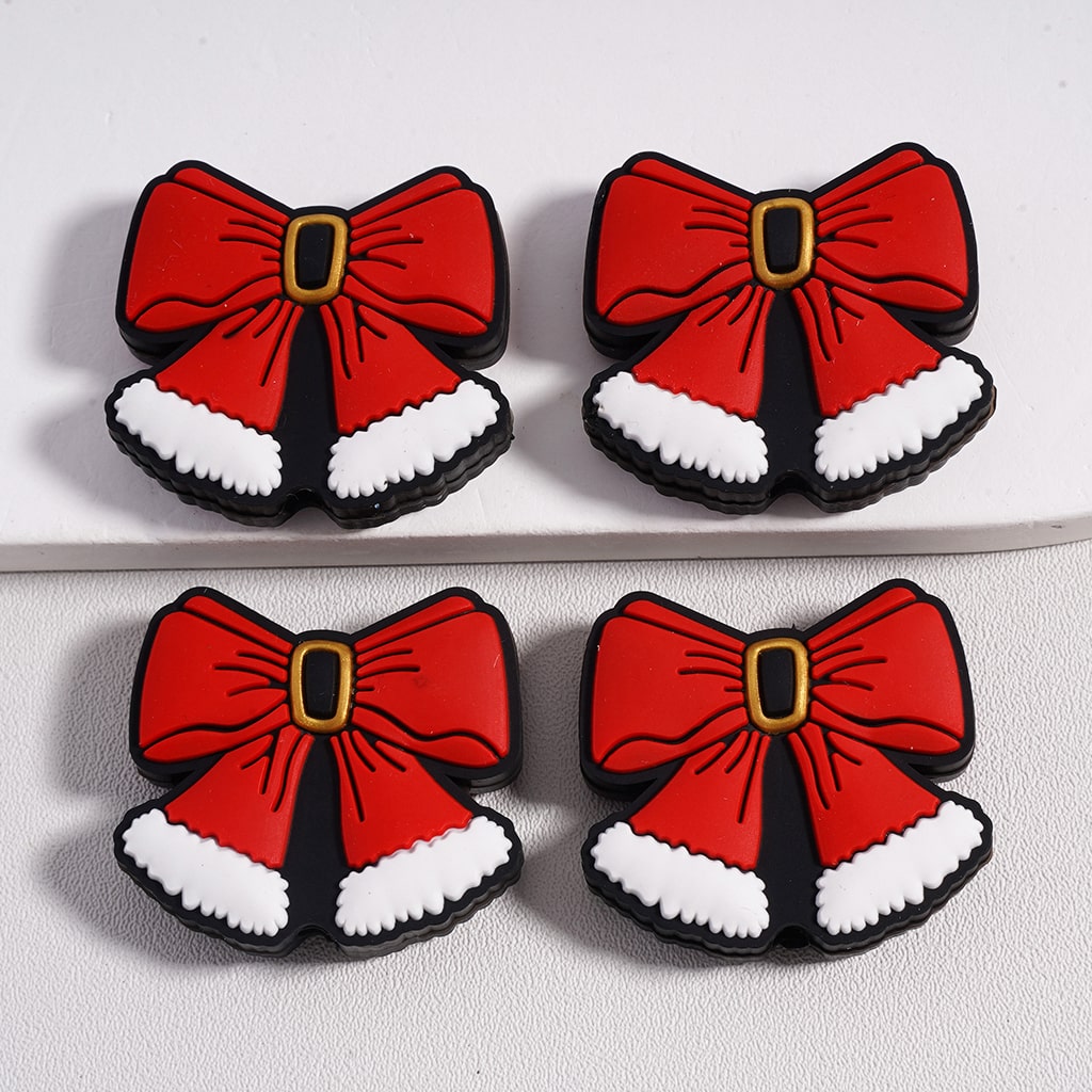 Four red bow-shaped cookies with black edges and white accents on a light gray background.

