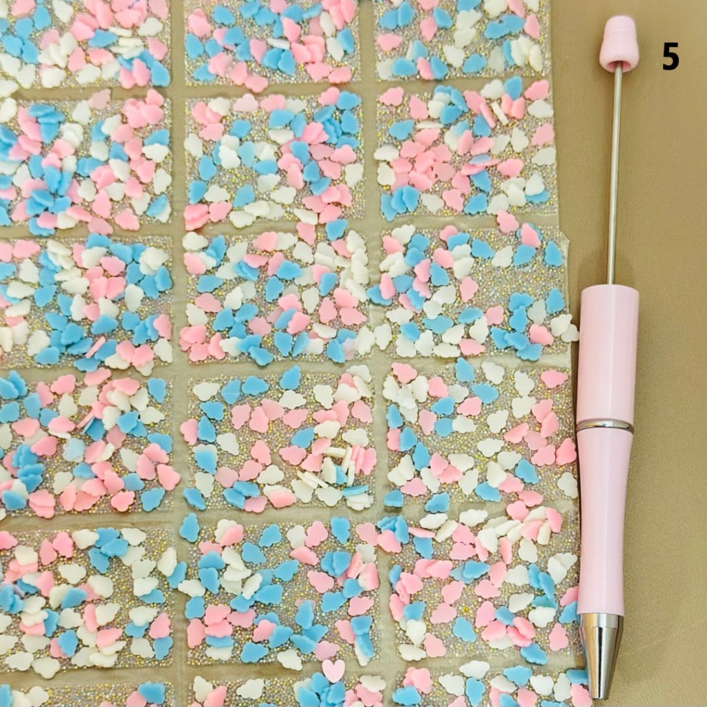 Pink pen on a surface with colorful confetti-like pattern

