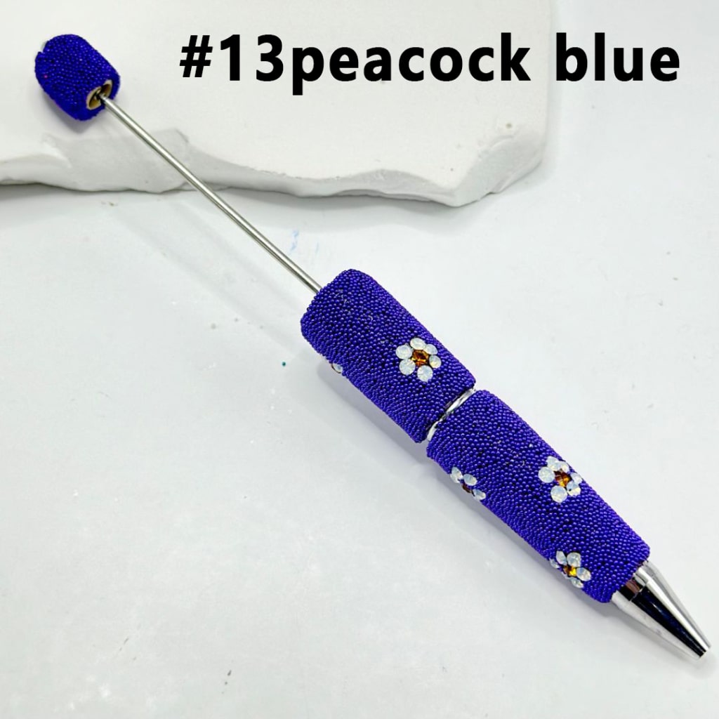 Decorative pen with blue beadwork on a white background

