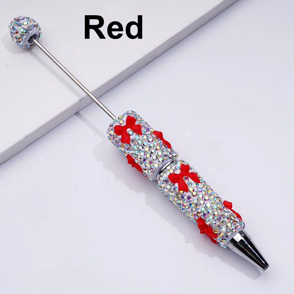 Decorative pen with red accents and gemstone embellishments on a white background

