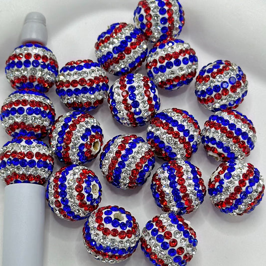 White round clay beads with a pattern of red and blue rhinestones, intended for use in arts and crafts.

