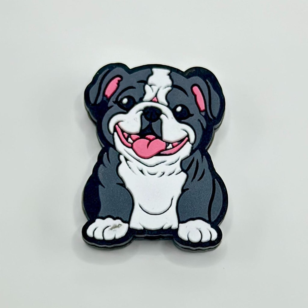 A silicone bead in the shape of a cartoon-style pug dog with black, white, and gray colors.

